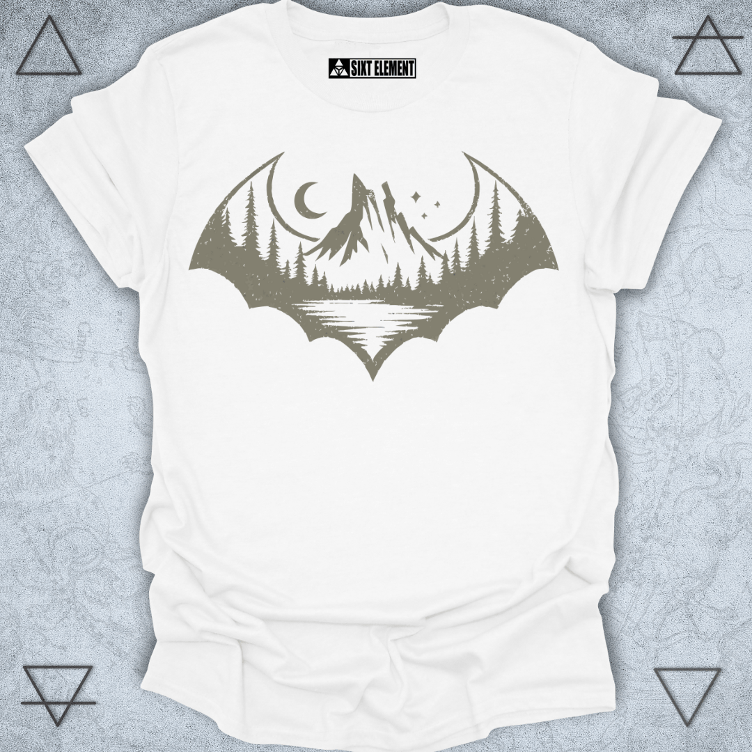 A distressed-style graphic shaped like a bat silhouette, featuring a scenic wilderness landscape inside. The design includes tall pine trees, a mountain range, a crescent moon, stars, and a reflection on a calm lake. The entire image has a rugged, vintage look, perfect for an outdoor or gothic-themed t-shirt.